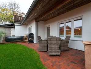 Eine Terrasse mit Korbmöbeln, einem Grill und einem Whirlpool.