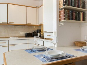 A modern kitchen with white cabinets, a coffee machine, and a dining area with a table set for two. - 4 in the House at Blanker-hans-weg 5 (St. Peter-Ording)
