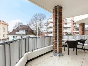 A balcony with a metal railing, a brick column, and a table with chairs. - 4 in the House at Blanker-hans-weg 5 (St. Peter-Ording)