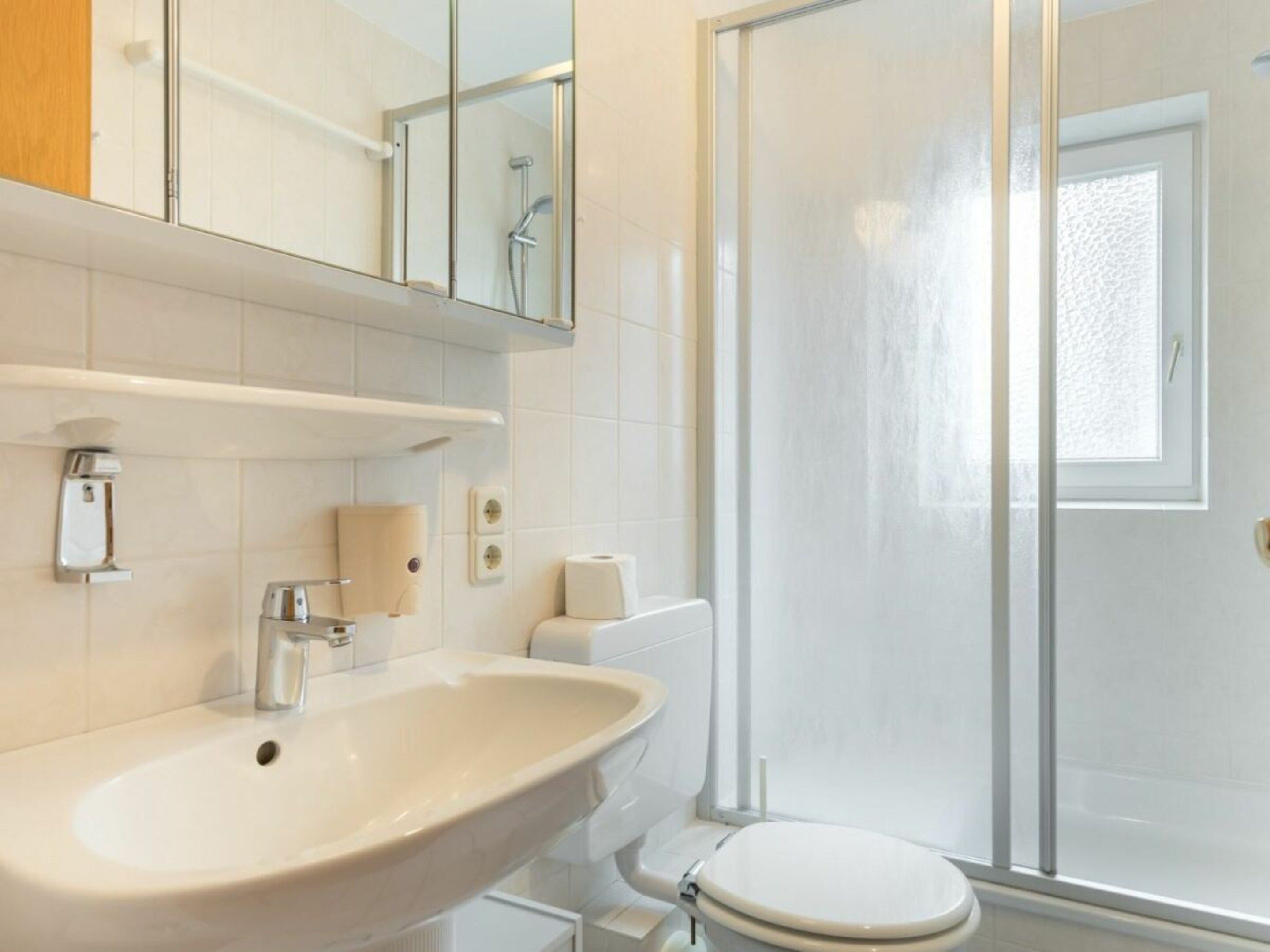 A bathroom with a sink, toilet, and a glass shower enclosure.