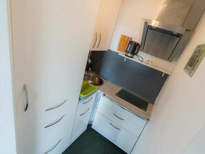 A compact kitchen with a stainless steel sink, a kettle, and a microwave. - Holiday Apartment 19 (St. Peter-Ording)