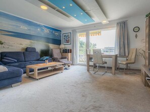 A living room with a sofa, coffee table, and a dining area with chairs. - Holiday Apartment 19 (St. Peter-Ording)