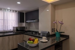 A modern kitchen with a microwave, toaster, and a bowl of fruit on the counter. - Departamento Orquídeas Elegancia, amplitud y privacidad una estancia excepcional (Ciudad de México)