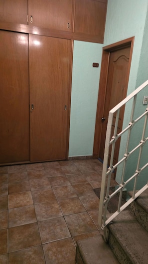 A room with a wooden wardrobe, a tiled floor, and a staircase with a metal railing. - Furnished Loft in Colonia Juárez, Alcaldía Cuauhté CDMX (Cuauhtémoc,)