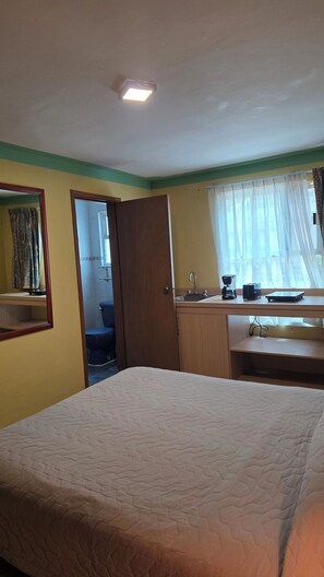 A hotel room with a bed, a bathroom with a toilet and sink, and a window with curtains. -  Loft Ejecutivo de Lujo - Maison Juárez Residencies (Cuauhtémoc,)