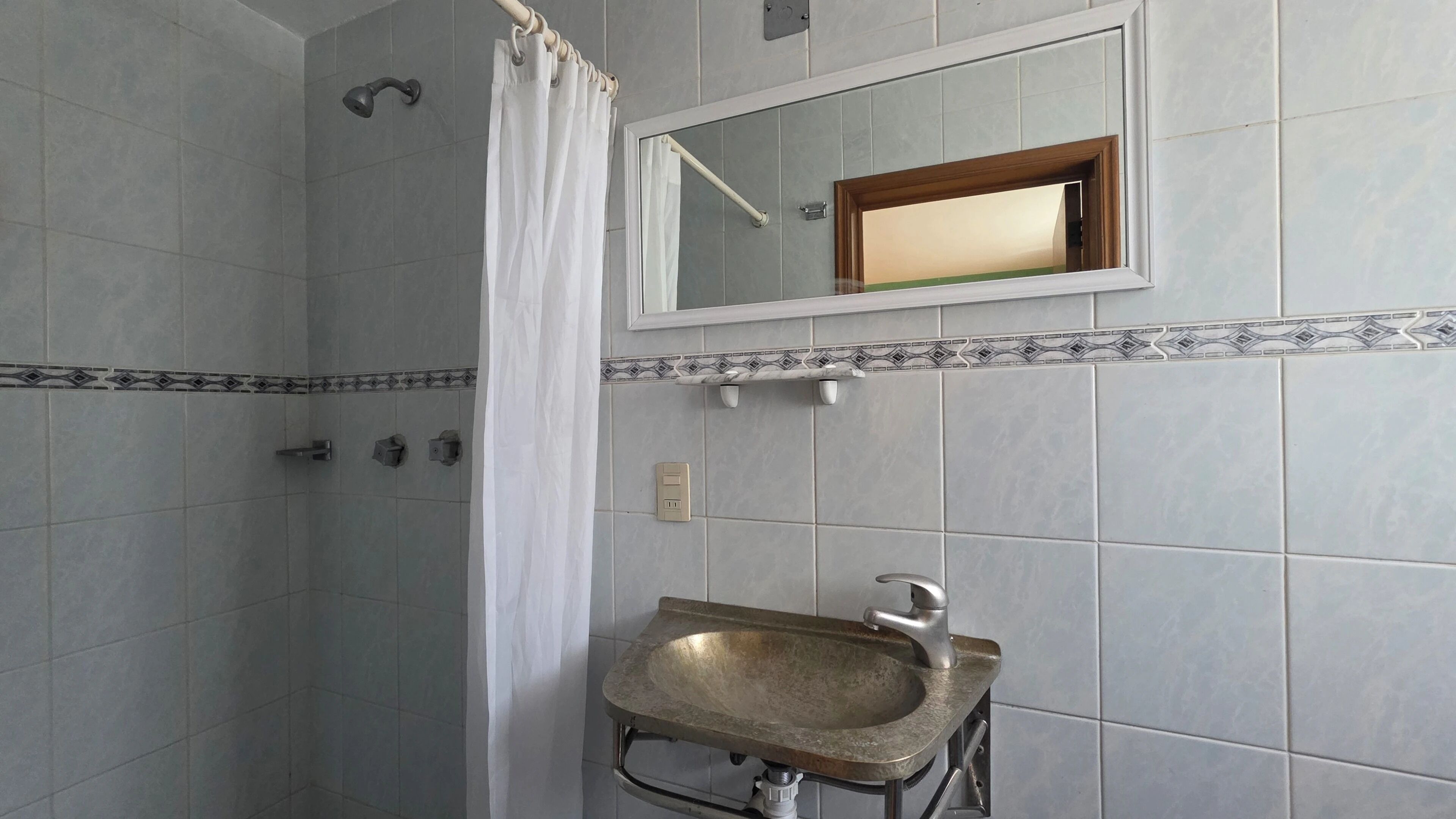Une salle de bain avec une douche, un lavabo et un miroir.