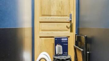 Un baño con puerta de madera, inodoro blanco y un taburete pequeño.