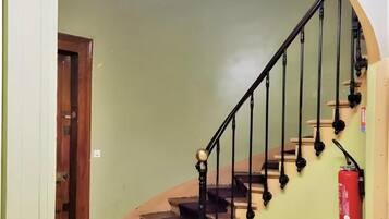 Una escalera con barandilla, un extintor y una puerta al final.