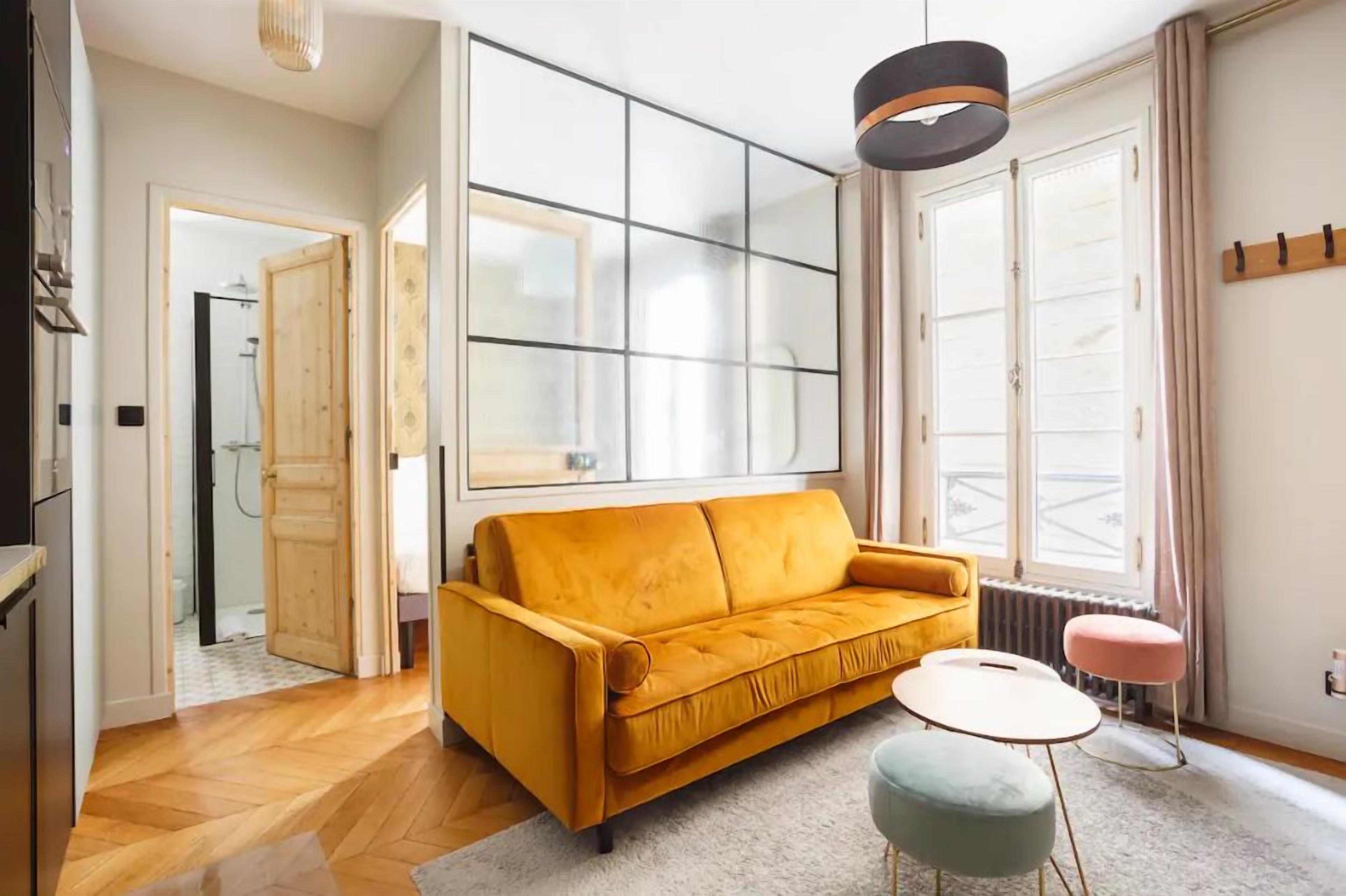 Un salon avec un canapé, une table basse et une grande fenêtre.