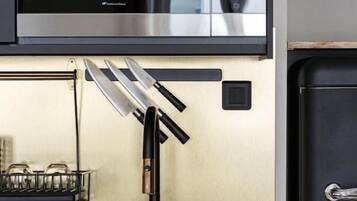 Una cocina con microondas de acero inoxidable, grifo negro y refrigerador negro.