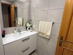A bathroom with a white sink, a mirror, a towel, and a door. - Your peaceful home in Funchal—enjoy the garden and the sea (funchal)