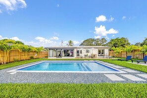 A residential property with a swimming pool, a patio with outdoor furniture, and a wooden fence. - Wilton Manors Waterfront Villa w/ Gorgeous Pool (Wilton Manors)