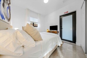 A hotel room with a bed, a desk with a computer, a TV, and a door marked 'EXIT'. - Wilton Manors Waterfront Villa w/ Gorgeous Pool (Wilton Manors)