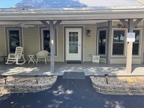 Ein Haus mit Veranda, einem Schaukelstuhl, einem kleinen Tisch und einem Schild, das einen Patio kennzeichnet.