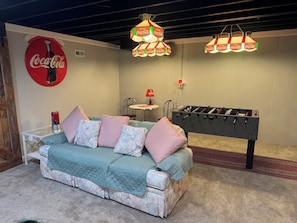 Ein gemütliches Zimmer mit einer Couch, einem Coca-Cola-Schild und einem Kicker.