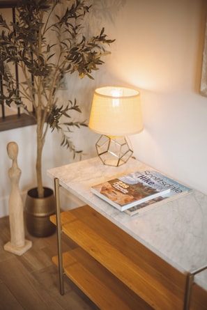 Et bord med et magasin, en lampe og en plante.