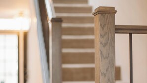 Eine Treppe mit Holzbalken und Handlauf, die zu einer Zwischenebene führt.