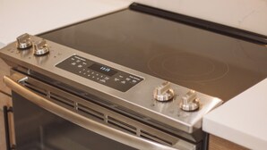 Ein Edelstahlbackofen mit digitaler Bedienblende, Glastür und einer Edelstahl-Dunstabzugshaube.