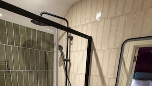 A bathroom with a glass-enclosed shower, a white sink with a black checkered floor, and a mirror reflecting a bed. - House Sleeps 8 With Parking and Balcony (Clones)
