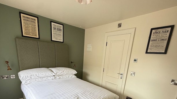 A bedroom with a bed, a headboard, a door, and framed certificates on the wall. - House Sleeps 8 With Parking and Balcony (Clones)