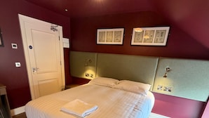 A neatly made bed with a folded towel, a door with a sign, and framed pictures on the wall. - House Sleeps 8 With Parking and Balcony (Clones)
