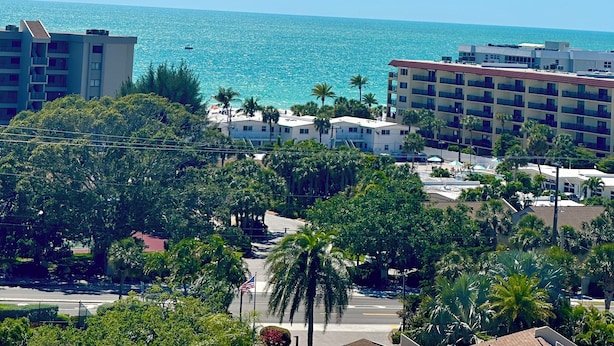 A coastal hotel with multiple buildings, a clear view of the ocean, and lush greenery. - Siesta Key Penthouse with Expansive Ocean Views (Siesta Key)