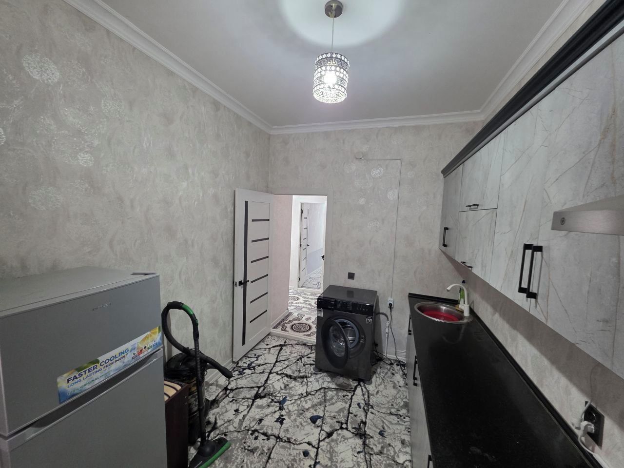 A compact kitchen with a washing machine, a refrigerator, and a sink.