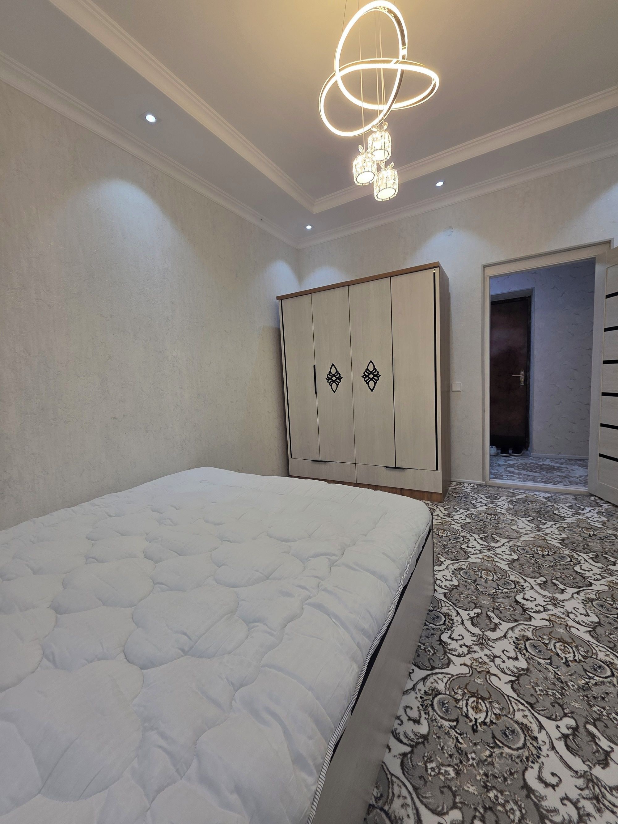 A bedroom with a bed, a wardrobe, and a patterned carpet.