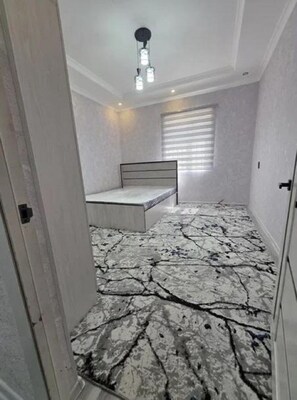 Quarto com cama, luminária no teto e janela com persianas.