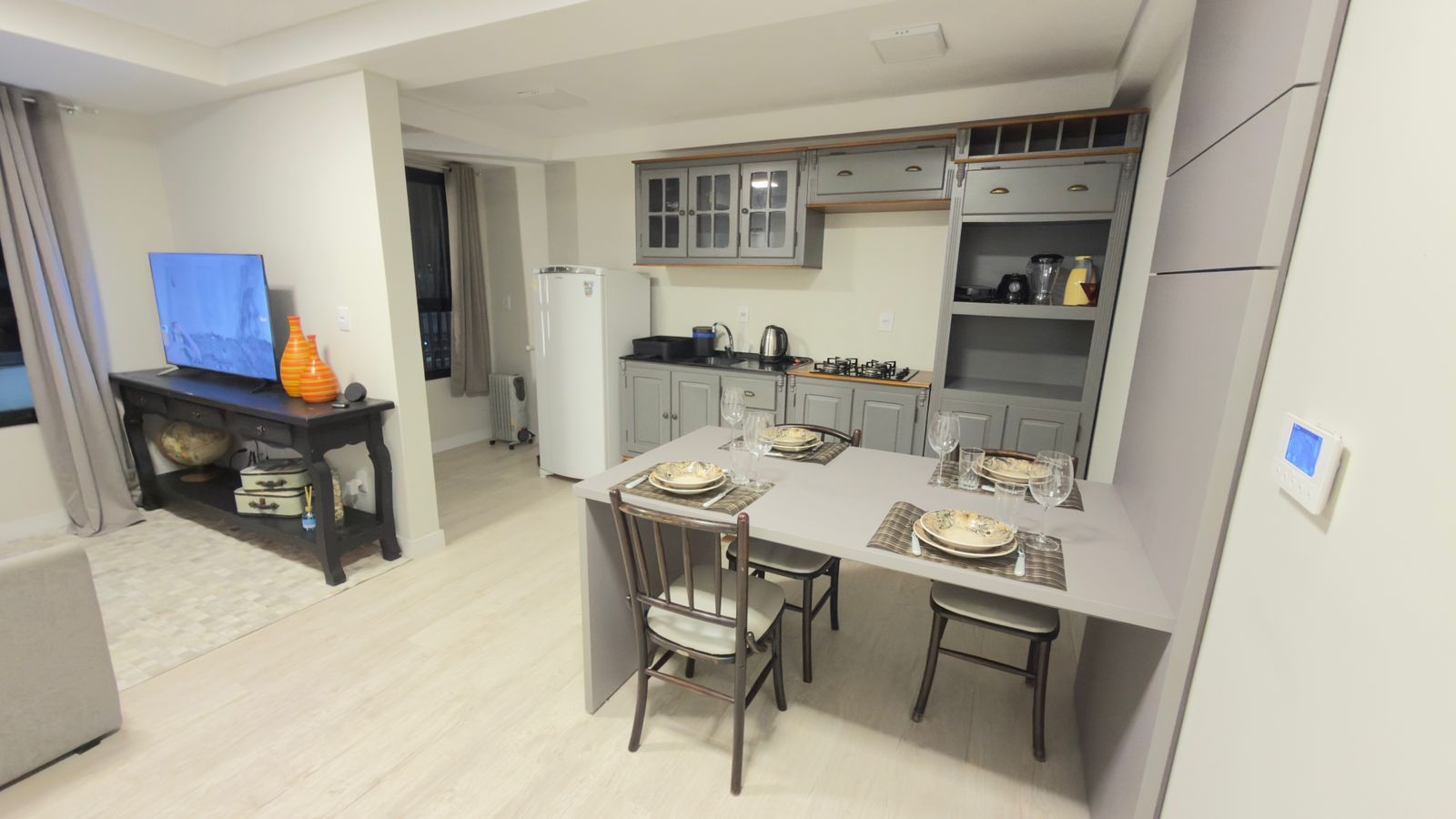 A compact kitchen with a dining area, a television, and a globe on a shelf.