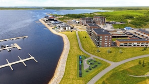 Ett flygbildsbild av en fastighet vid vattnet med en brygga, byggnader och grönområden.
