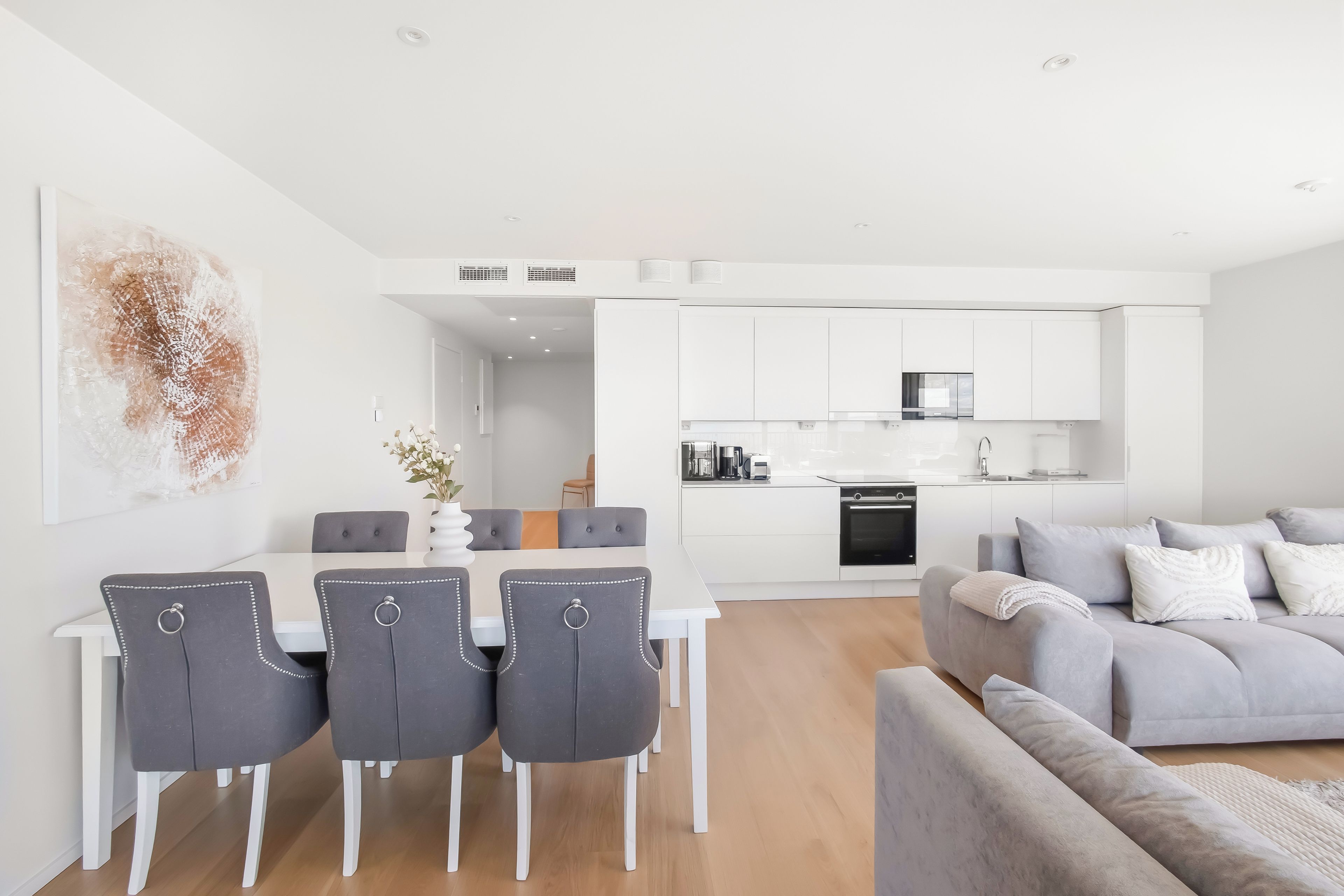 A modern kitchen with white cabinets and a built-in oven.