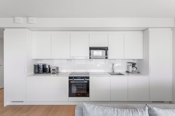 Una cocina moderna con armarios blancos, microondas integrado, cafetera y horno Siemens.
