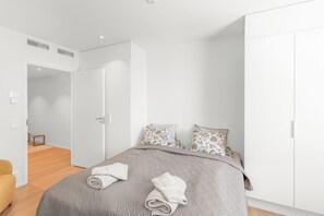 A modern bedroom with a bed, pillows, and a neatly folded towel.
