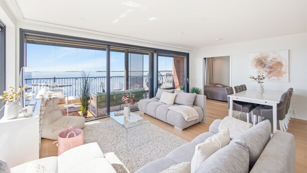A spacious living area with a large window, a sofa, a coffee table, and a dining table. - Stunning beachfront apartment for 1-8 people in Oulu Pateniemenranta. (Oulu)