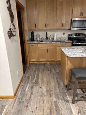 A kitchen with wooden cabinets, a granite countertop, a stainless steel oven, and a herringbone-patterned floor. - Ben's Place - A Quiet Sanctuary where you can enjoy sunrises and sunsets. (Sonoita)