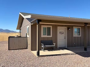 A single-story building with a front door, a bench, and a small porch area. - Ben's Place - A Quiet Sanctuary where you can enjoy sunrises and sunsets. (Sonoita)