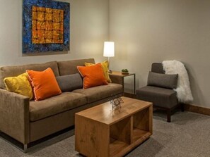 A living room with a sofa, a coffee table, a lamp, and a painting on the wall. - Ski-In/Ski Out 1-bedroom condo with amazing amenities in beautiful Breckenridge (Breckenridge)