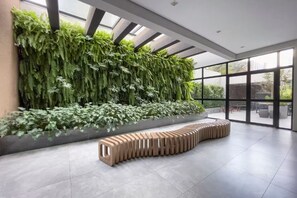 A modern interior with a vertical garden, a unique seating area, and large windows. - Wire Capote Valente (São Paulo)