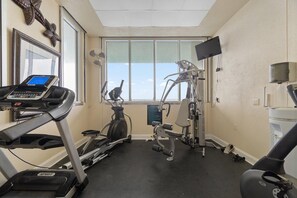A gym with a treadmill, elliptical, and weight machine. - Windemere 405 (Pensacola)