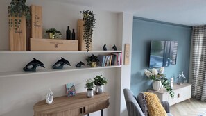 Ein Wohnzimmer mit Bücherregal, Dekoration, einem Fernseher und einem gestreiften Sofa.