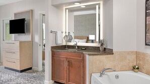 A modern bathroom with a granite countertop, a white sink, a mirror, and a bathtub. - Perfectly positioned within one of the top 25 destinations in the U.S. (Myrtle Beach)
