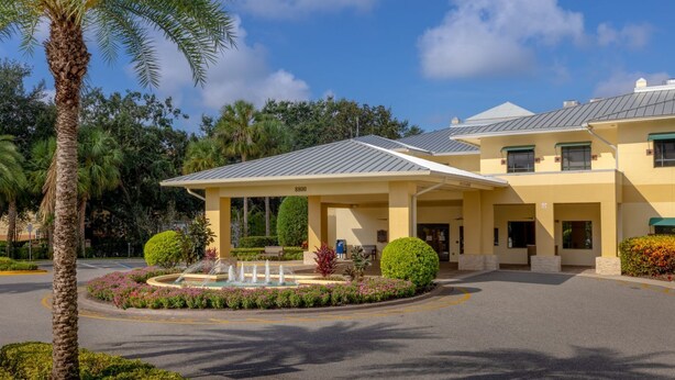 A hotel with a covered entrance, palm trees, and a fountain in the courtyard. - Perfectly positioned within one of the top 25 destinations in the U.S. (Myrtle Beach)
