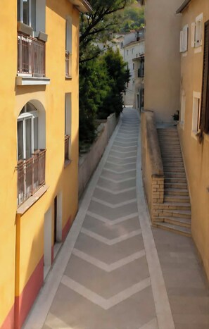 A narrow street with buildings on either side, a clear sky, and a staircase leading to a higher level. - Old Square Senj apartment: the authentic atmosphere of the old coastal town. (Senj)