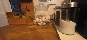 Una encimera de cocina con un tarro de cristal lleno de galletas, una caja de té Darjeeling y dos recipientes de acero inoxidable.