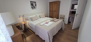 A hotel room with a bed, bedside tables, a wardrobe, and a door leading to a bathroom. - Old Square Senj apartment: the authentic atmosphere of the old coastal town. (Senj)