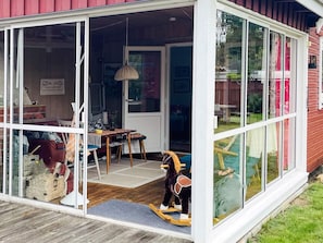 A covered outdoor area with a wooden deck, a table with chairs, and a rocking horse. - 5 Person Holiday Home in Solvesborg (Sölvesborg)