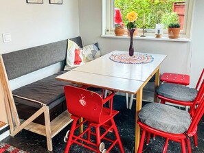 A room with a sofa, a small table, and two chairs. There is a window with plants on the sill. - 5 Person Holiday Home in Solvesborg (Sölvesborg)