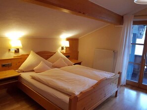 A single bed with a wooden headboard, two bedside lamps, and a window with curtains. - Starry sky - Groller Holiday Farm (Drachselsried)