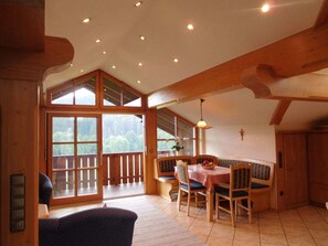 A dining area with a table and chairs, a bench, and a view through large windows. - Starry sky - Groller Holiday Farm (Drachselsried)